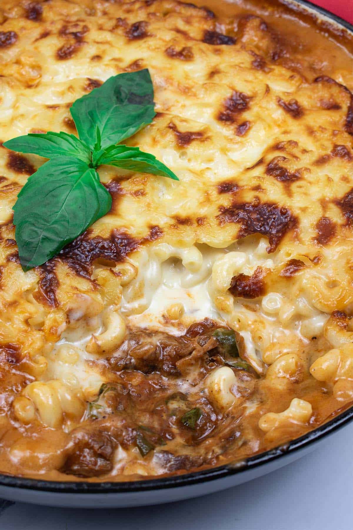 Close up of mac 'n' cheese with rich beef ragu in a large round casserole.