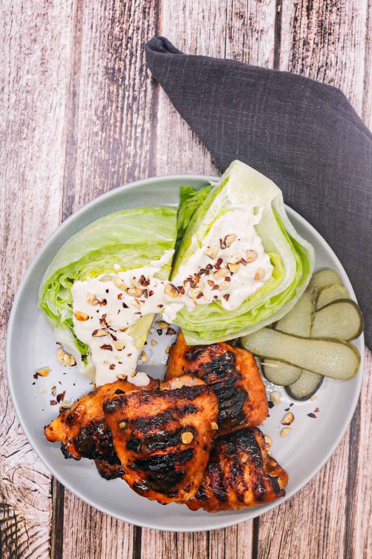 BBQ buffalo chicken thighs with wedged ranch salad on a grey dinner plate, with a grey napkin on the side.