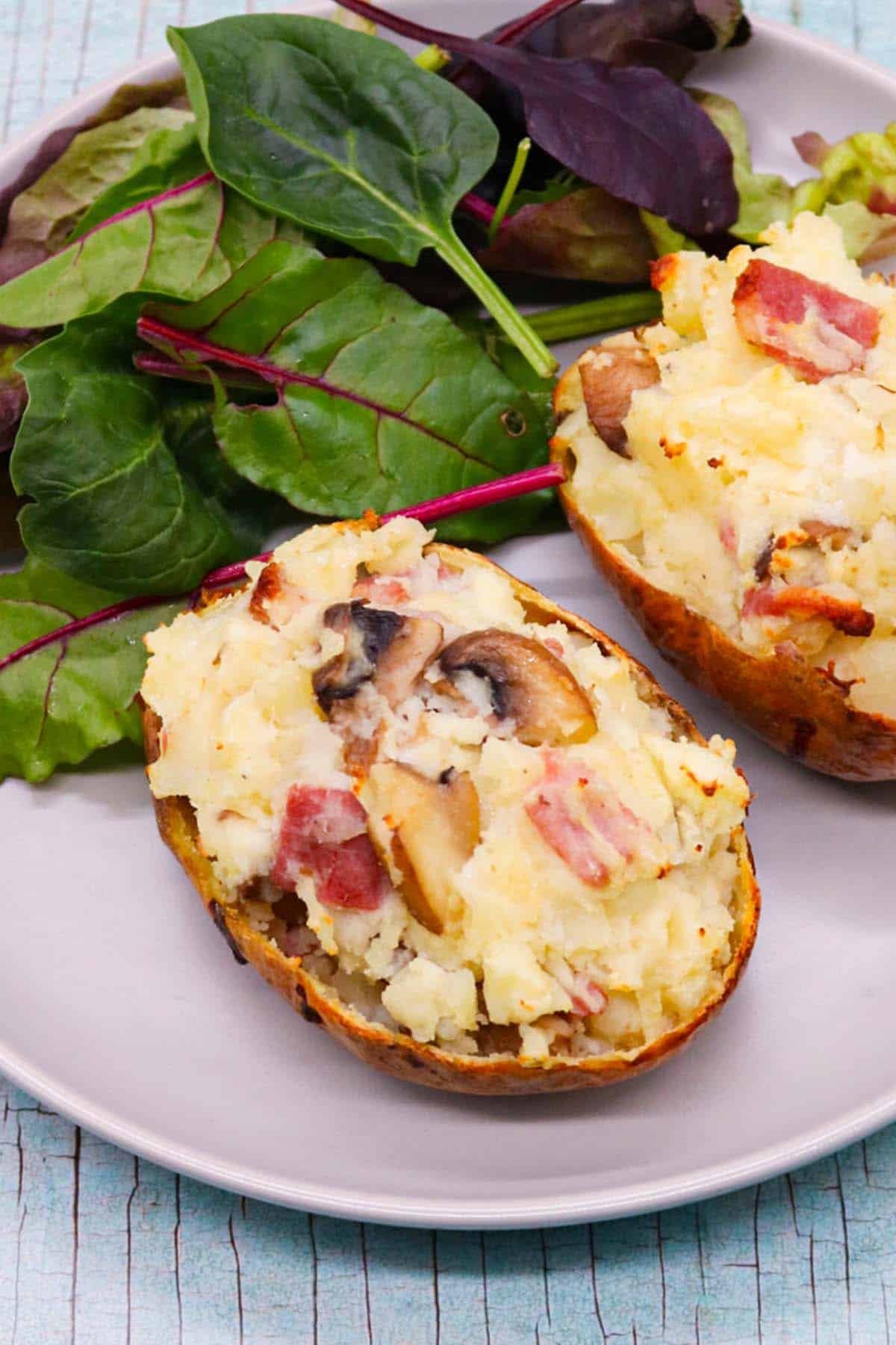 Bacon and mushroom baked potato on grey plate with salad leaves