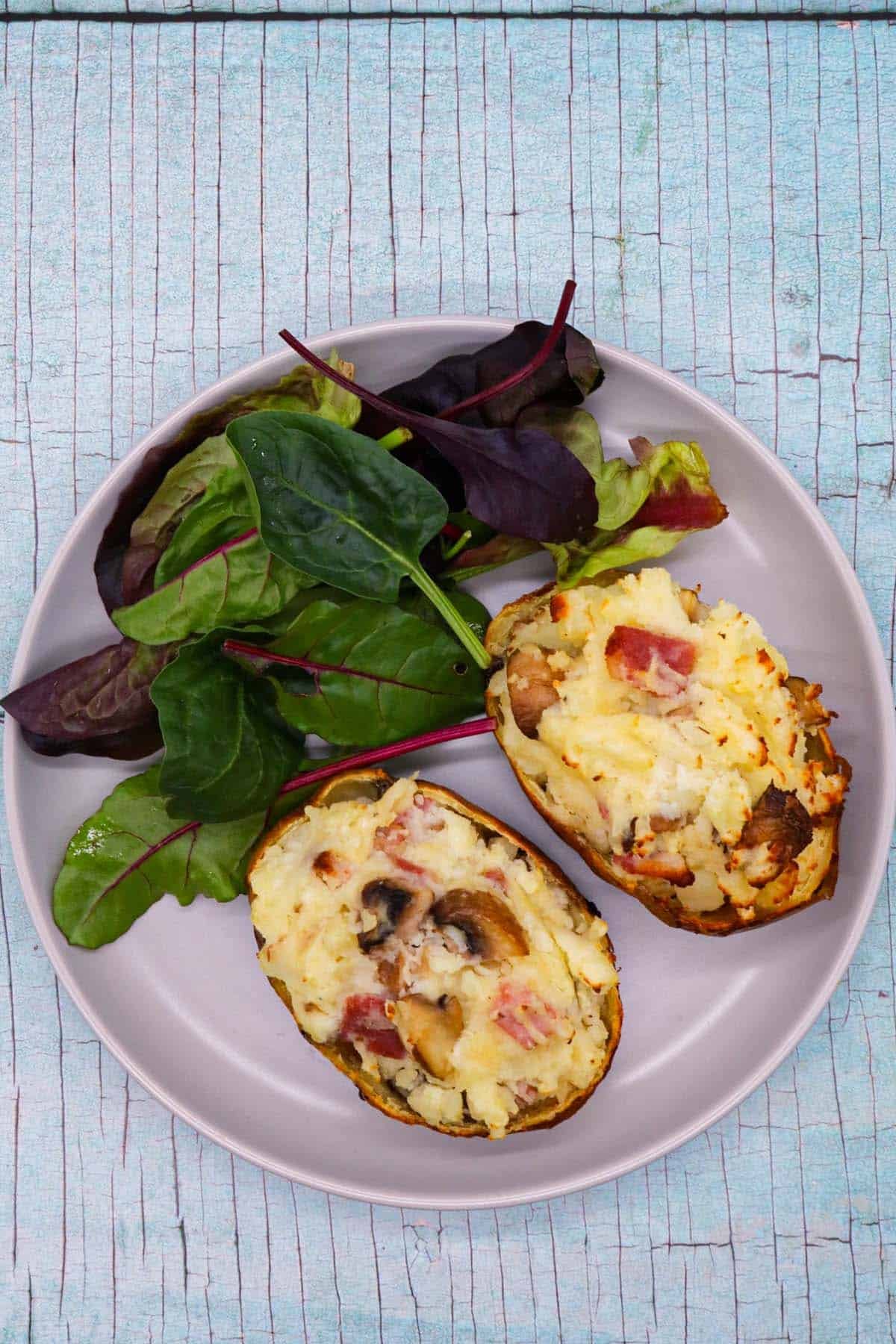 Bacon and mushroom baked potato on grey plate with salad leaves