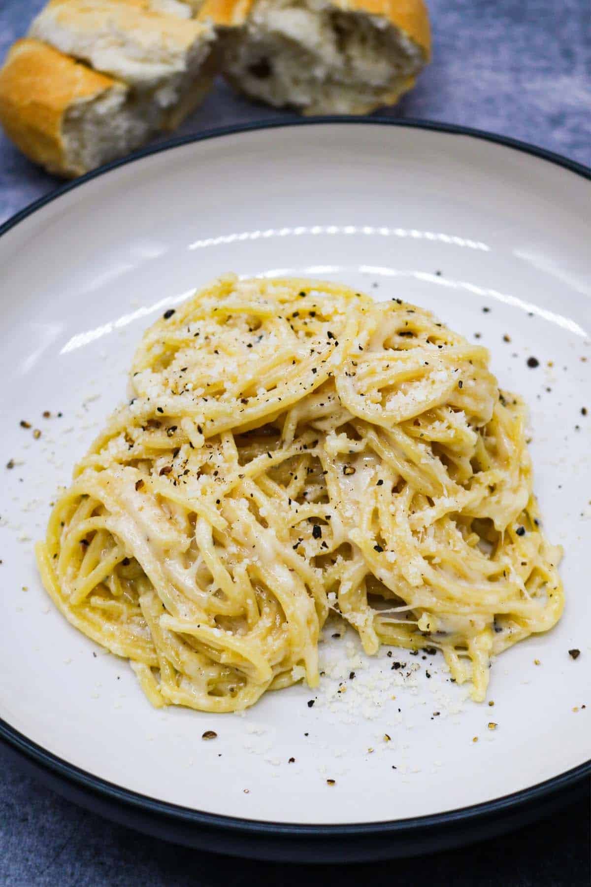 cacio e pepe in bowl with bread in background