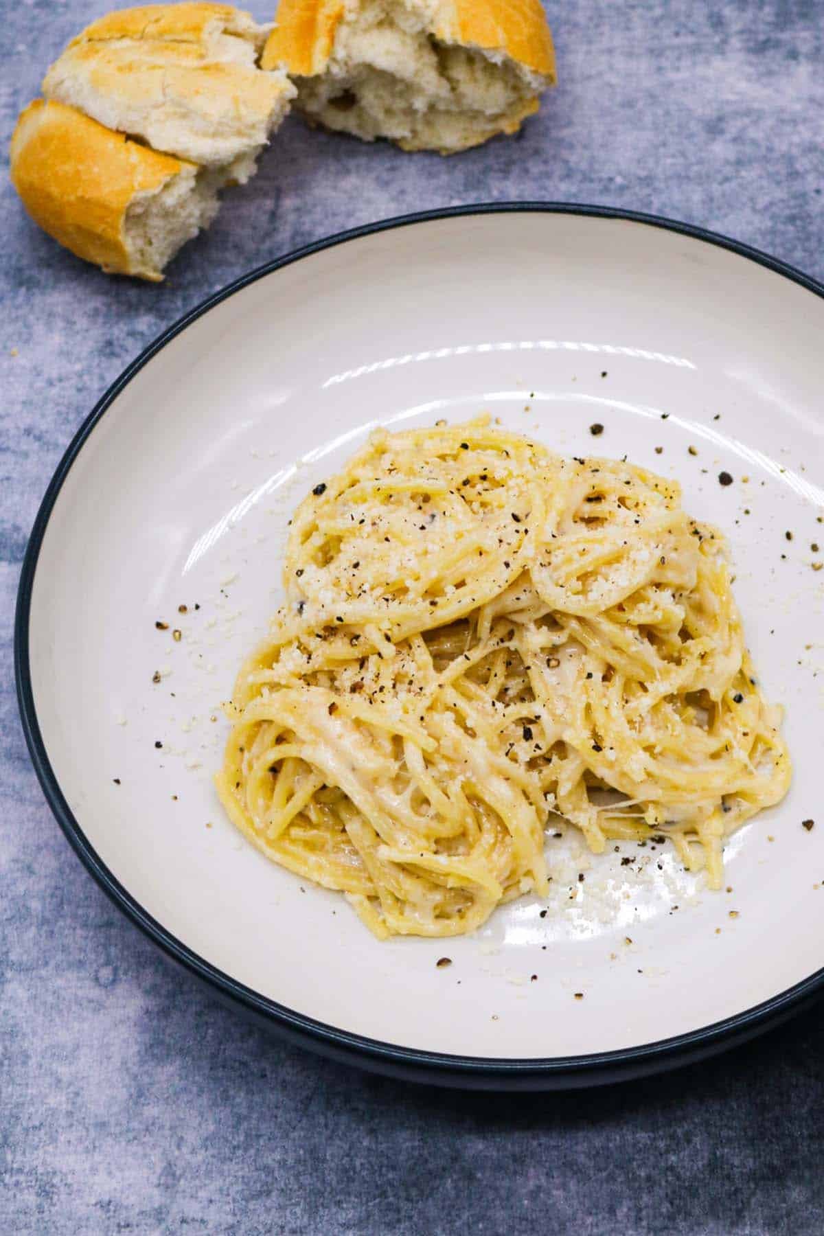 cacio e pepe in bowl with bread in background