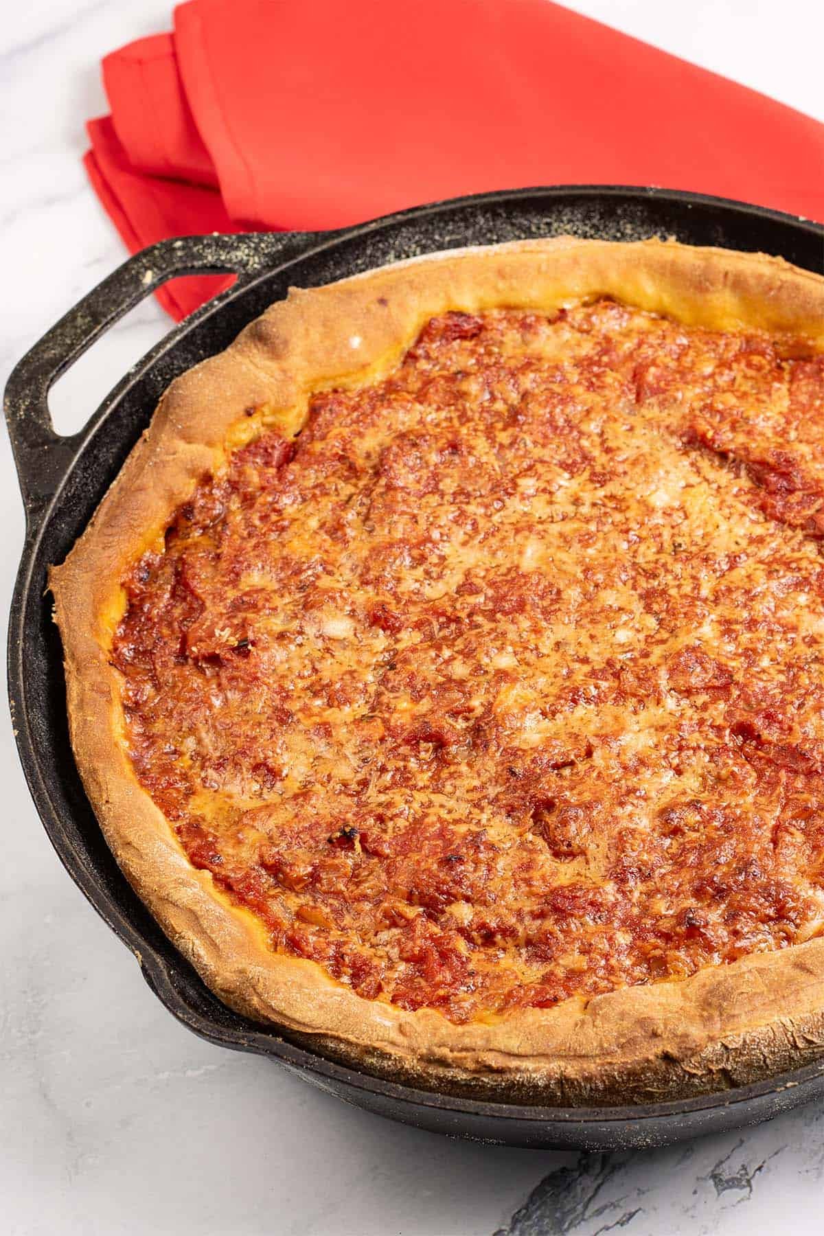 Chicago deep pan pizza in a black skillet with a red napkin on the side.