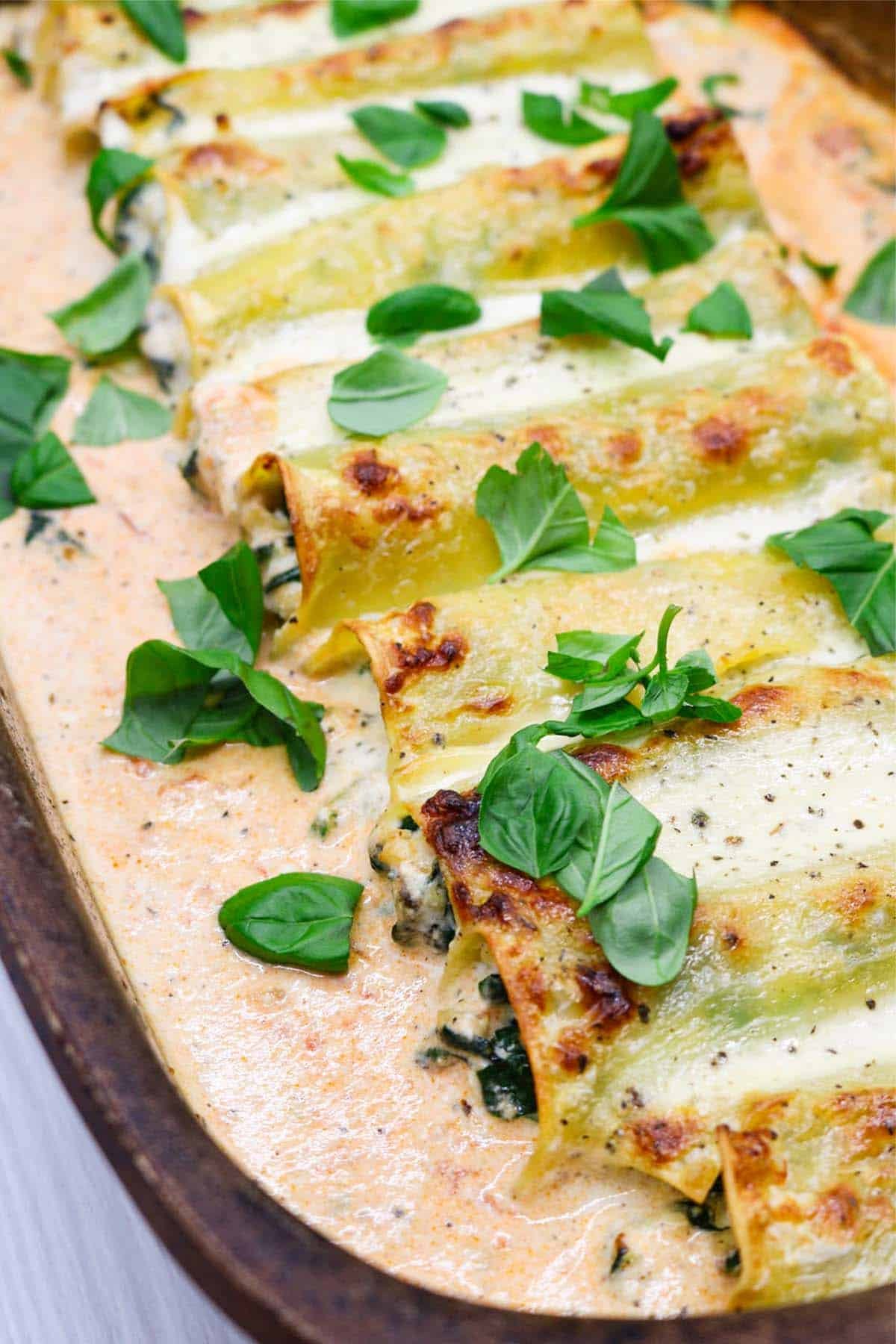 Close up of chicken, spinach and ricotta cannelloni in a large ovenproof dish.