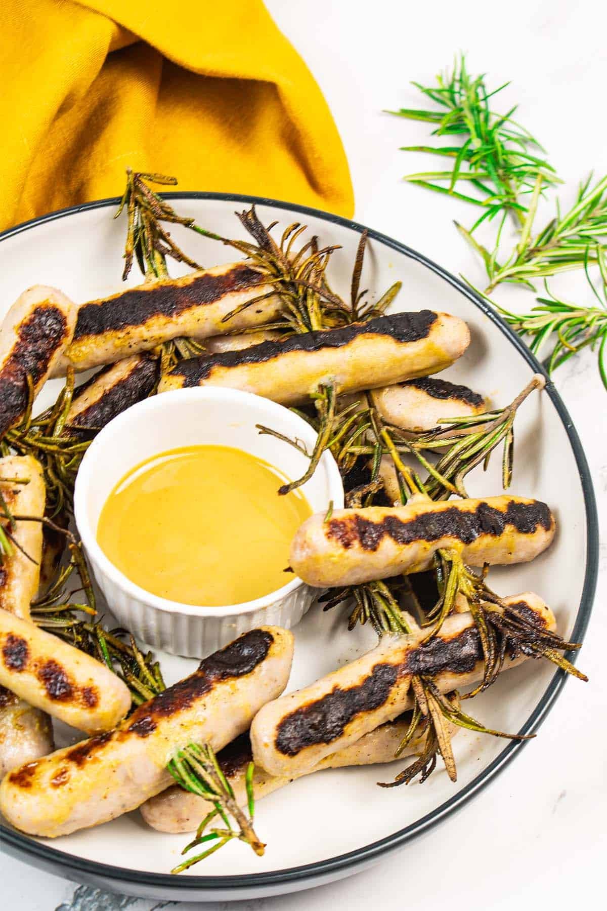 Chipolata rosemary skewers in a bowl with honey mustard dressing