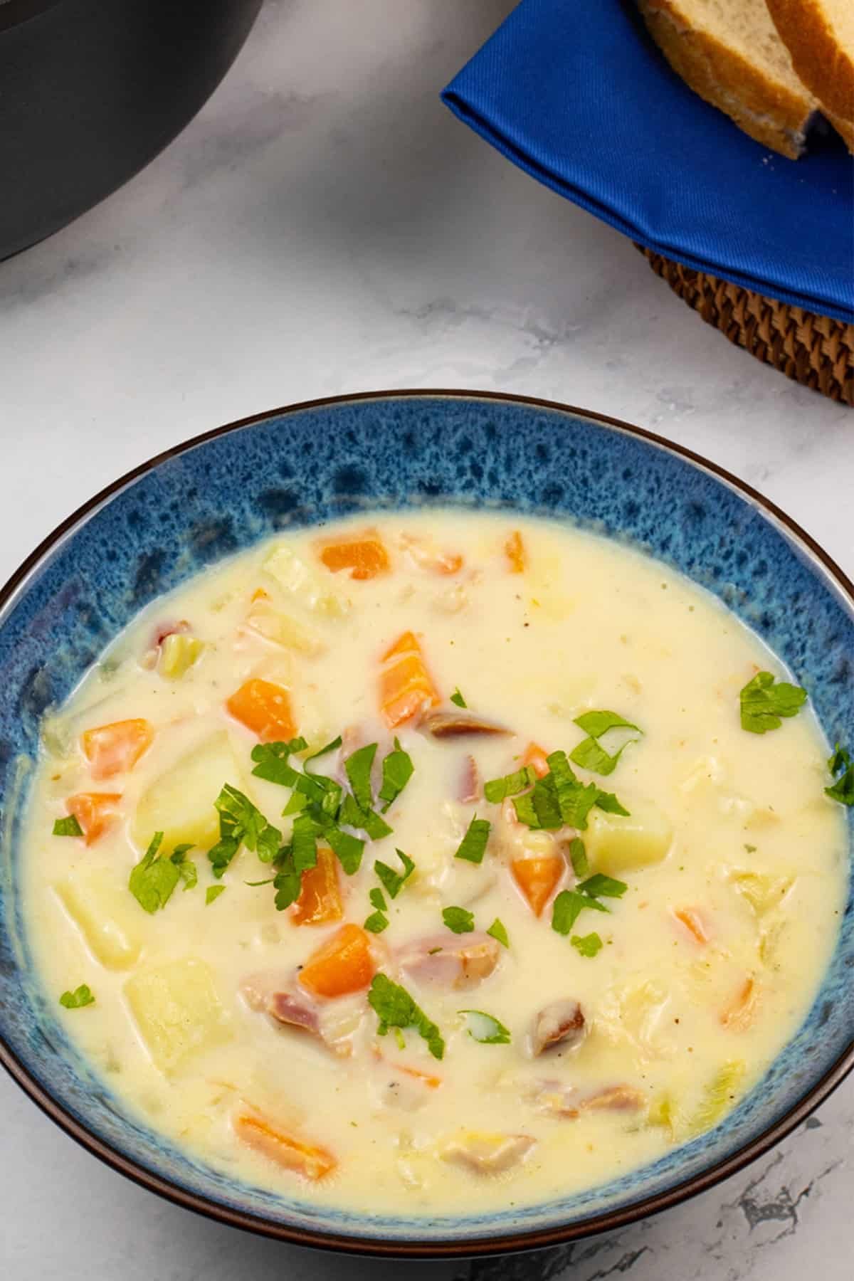 Close up of creamy ham and potato soup in a blue patterened bowl.