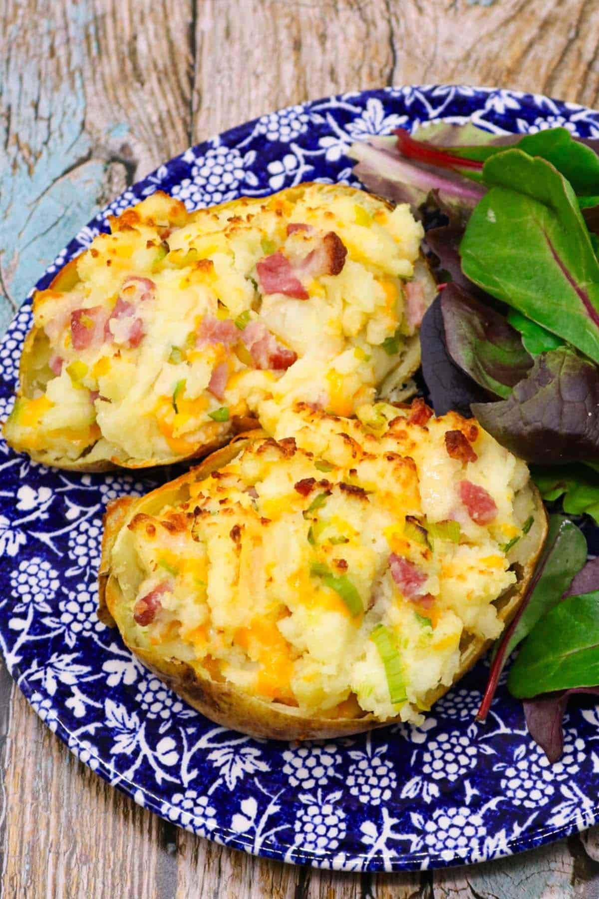 leek and bacon baked potato on blue and white plate with salad leaves