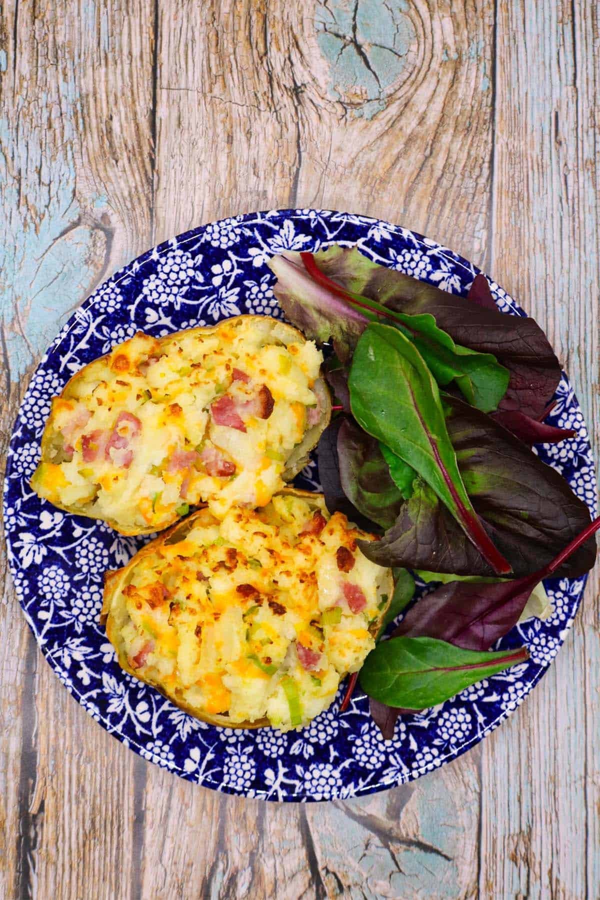 leek and bacon baked potato on blue and white plate with salad leaves