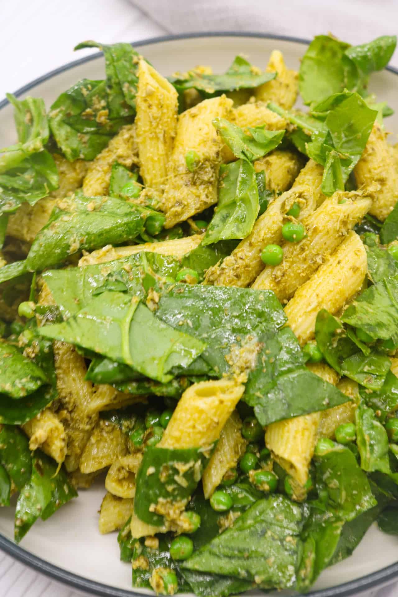 Close up of pesto, peas and spinach pasta salad in large bowl