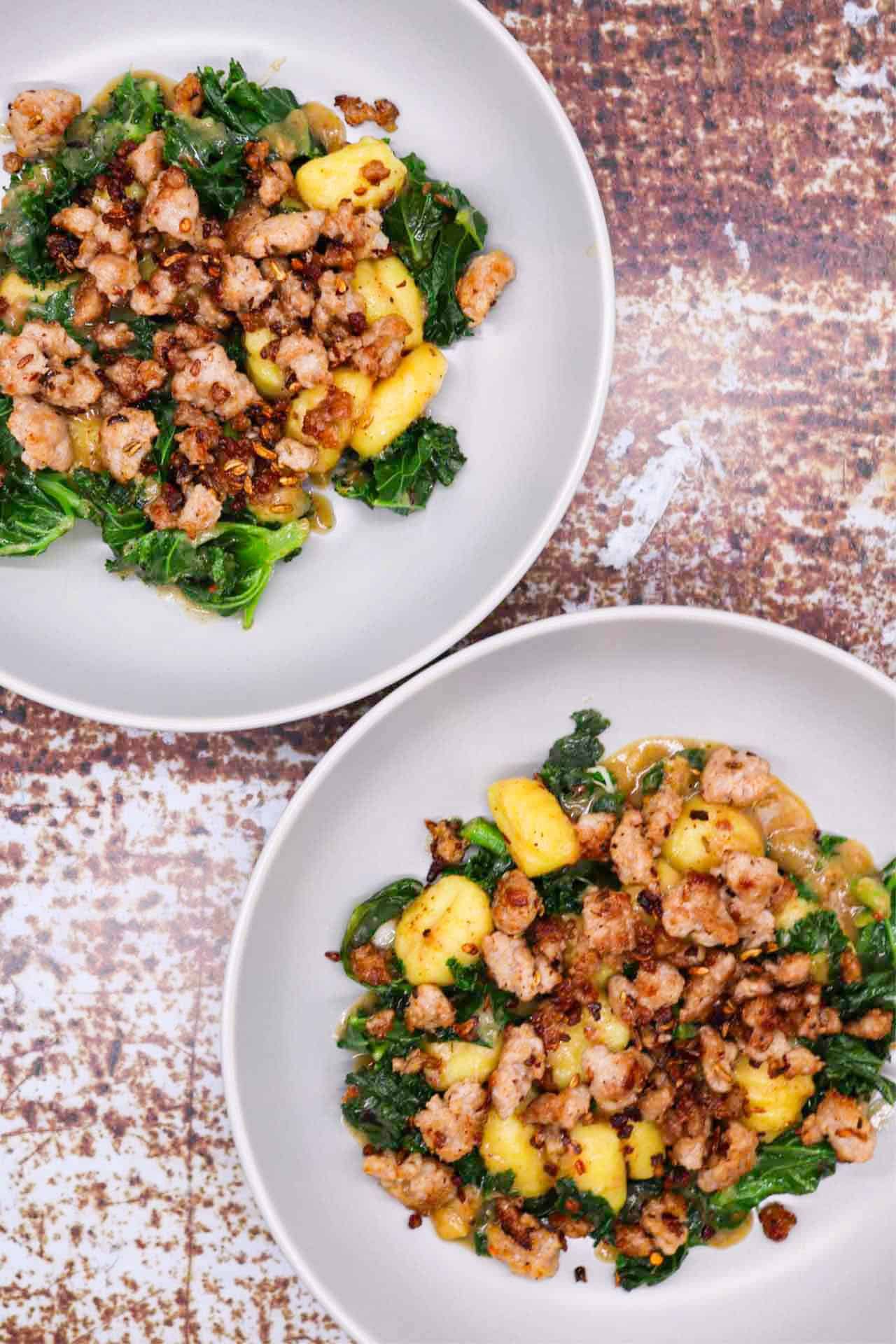 Two grey bowls of sausage, kale and gnocchi one pot.