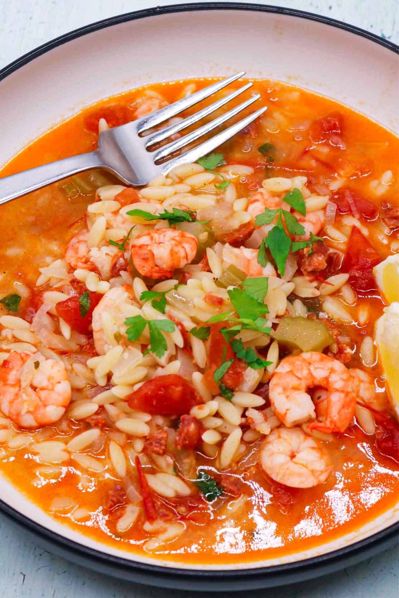 Slow cooker prawn and chorizo paella in bowl with lemon wedges and a fork