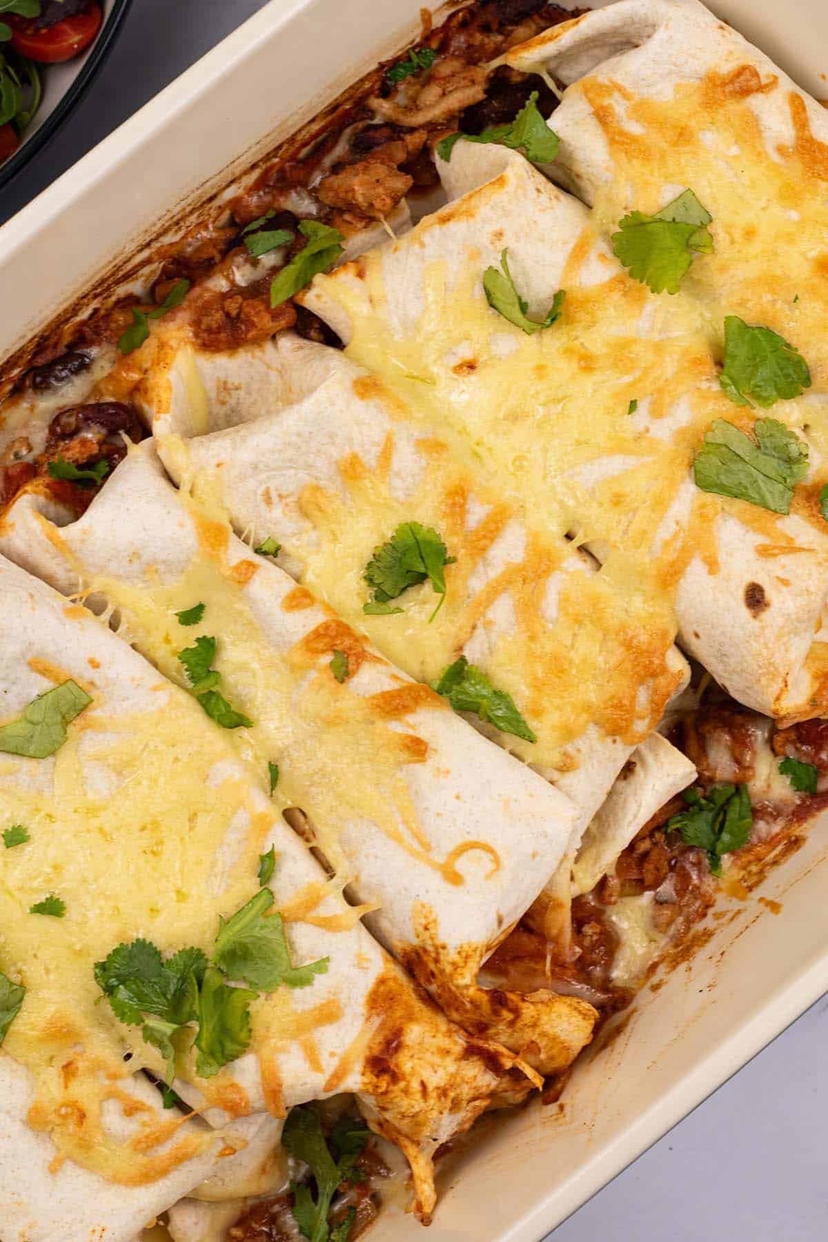 Close up of turkey enchiladas in a large rectangle oven dish.
