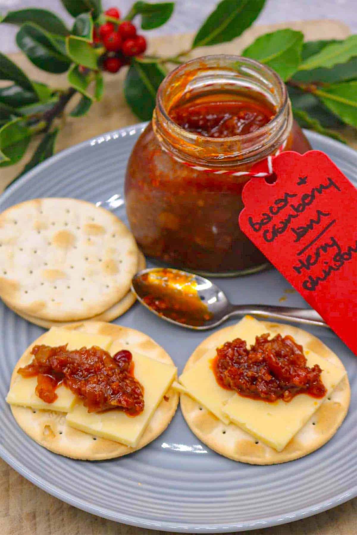 Plate with crackers spread with bacon and cranberry jam and cheese with jar
