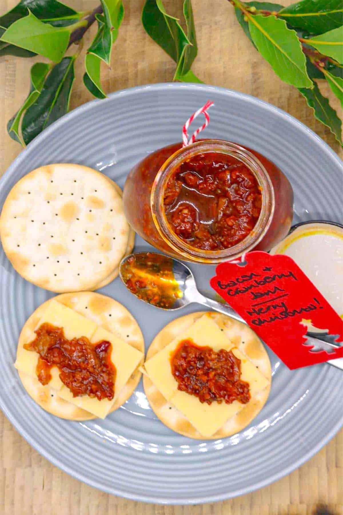 Plate with crackers spread with bacon and cranberry jam and cheese with jar