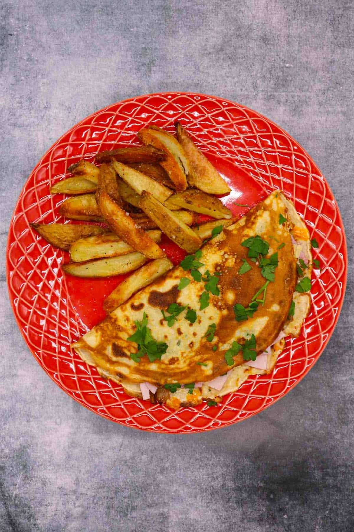 Cheese and ham pancake on red plate with chips