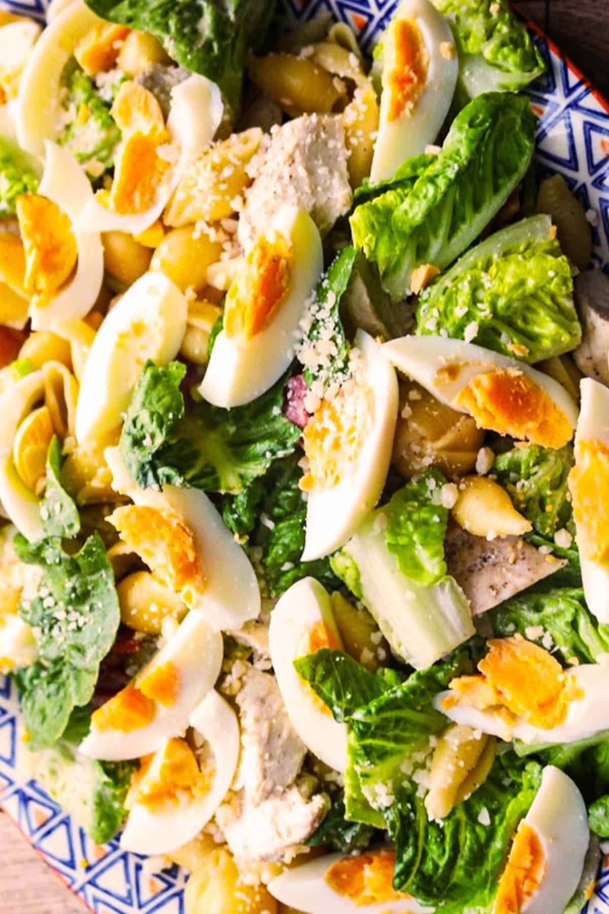 Close up of chicken caesar pasta salad made in the Thermomix on large blue, white and orange patterned serving platter.