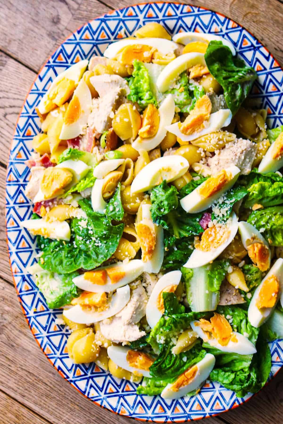 Chicken caesar pasta salad made in the Thermomix on large blue, white and orange patterned serving platter.