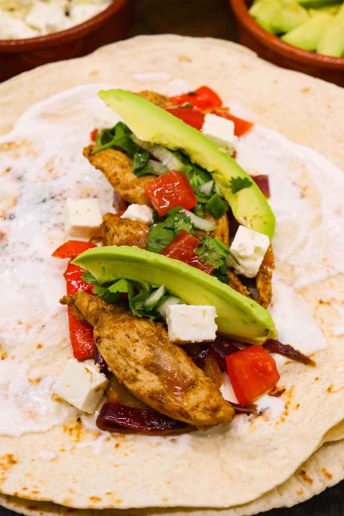 Chicken fajita on flour tortilla with avocado and cheese