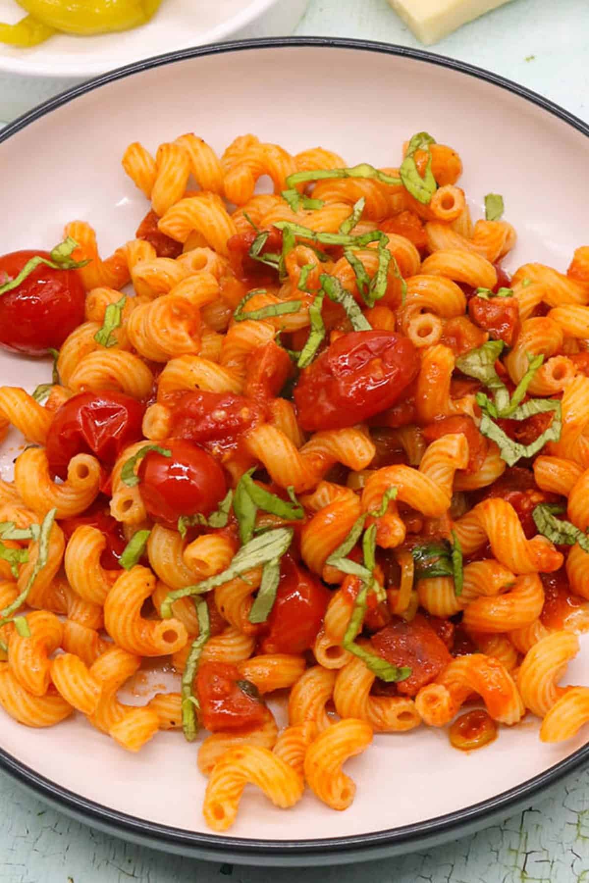 Chorizo and chilli pepper pasta in a black and cream bowl.