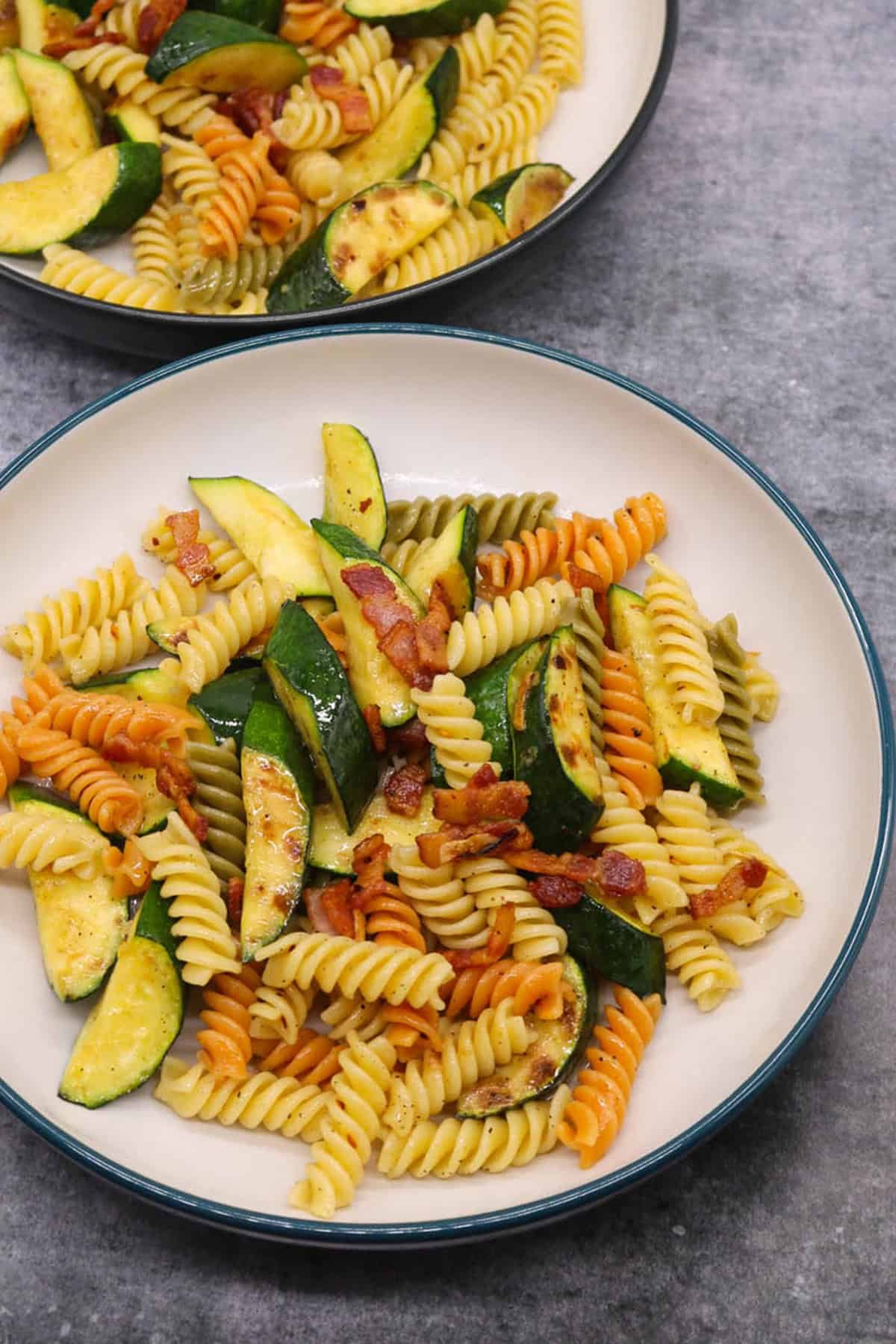 Two bowls of chargrilled courgette and smoked bacon pasta.
