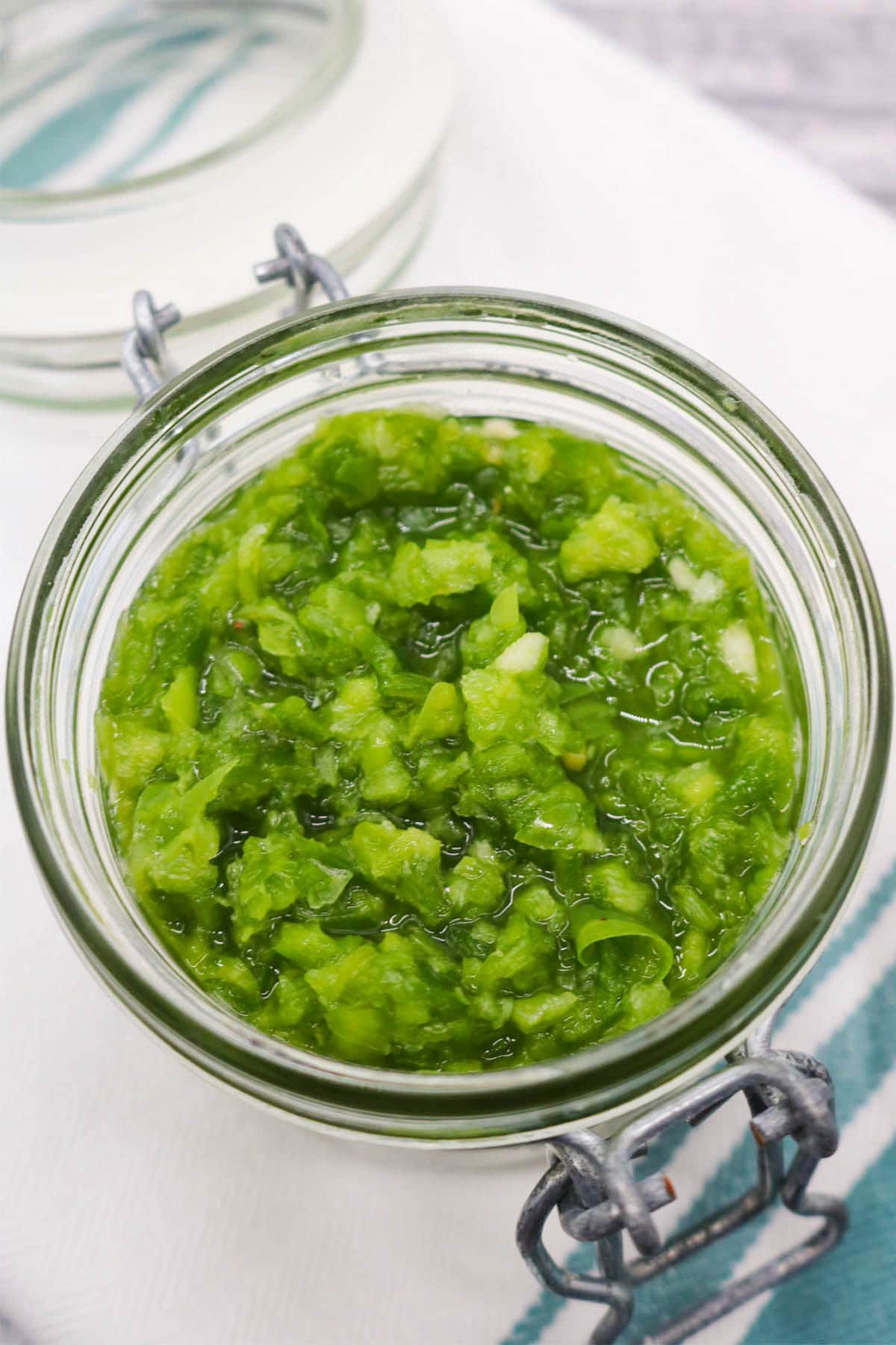 Fresh jalapeño relish in jar on green and white towel