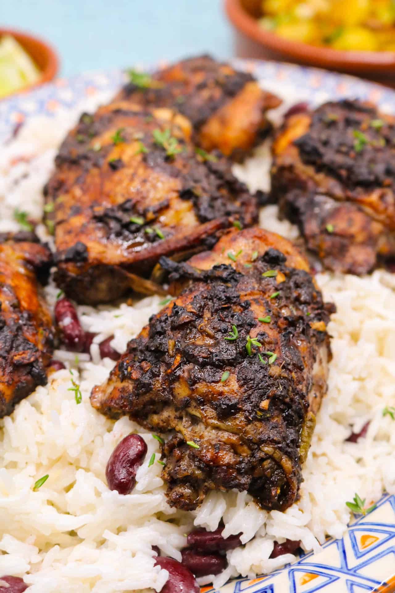 erk chicken with coconut rice on oval platter next to charred pineapple and spring onions in bowl