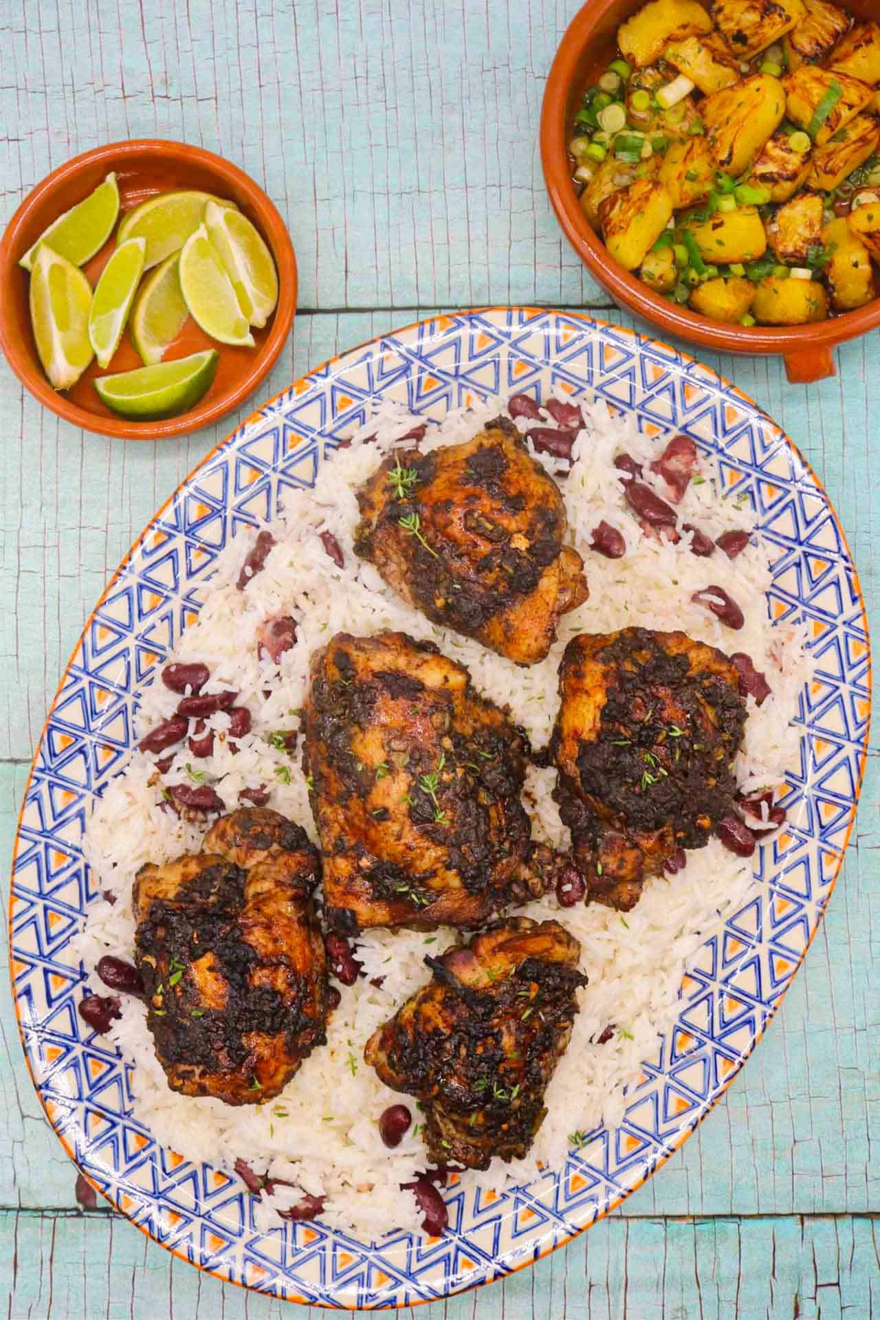 erk chicken with coconut rice on oval platter next to charred pineapple and spring onions in bowl