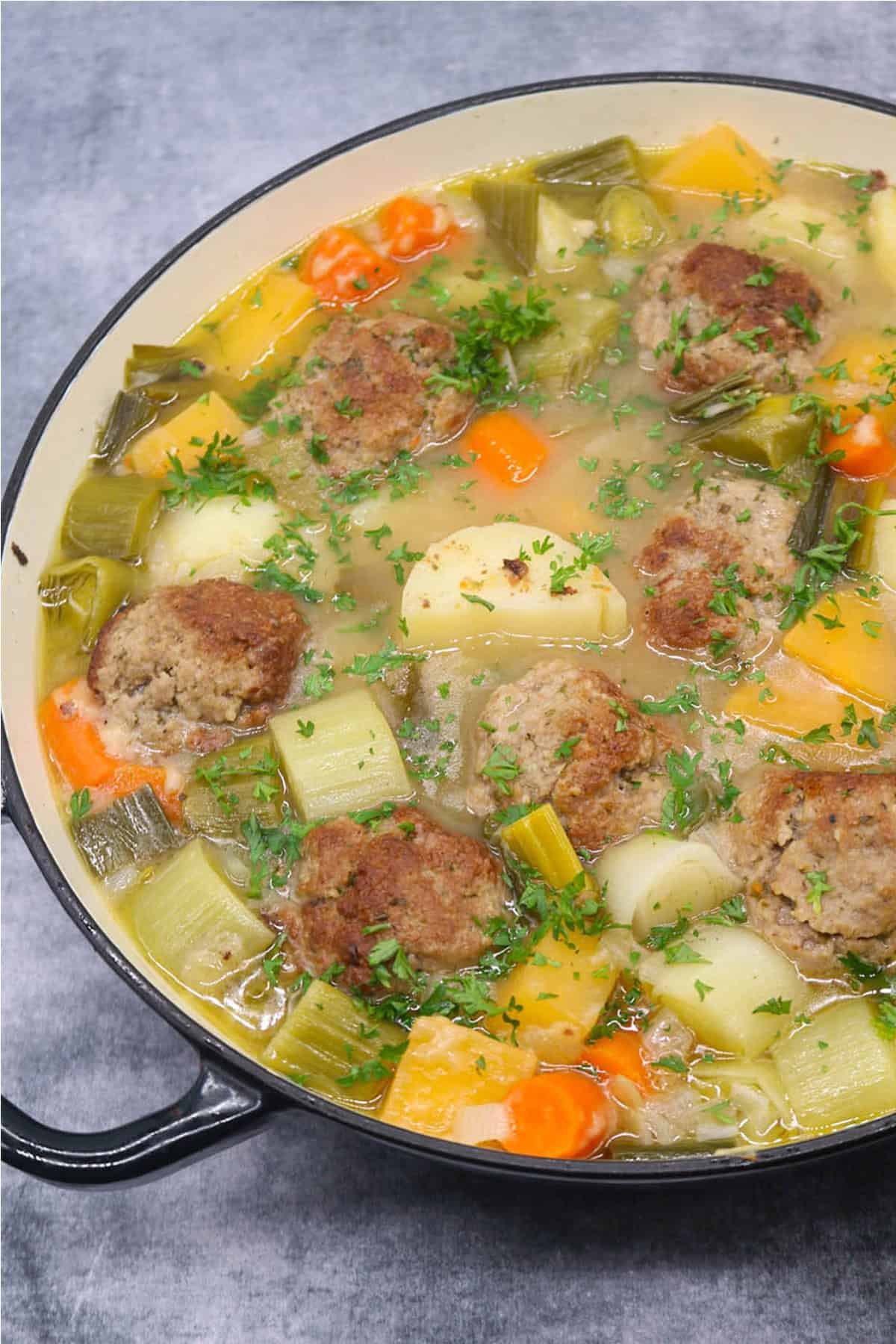 Lamb meatball cawl in a large round casserole.