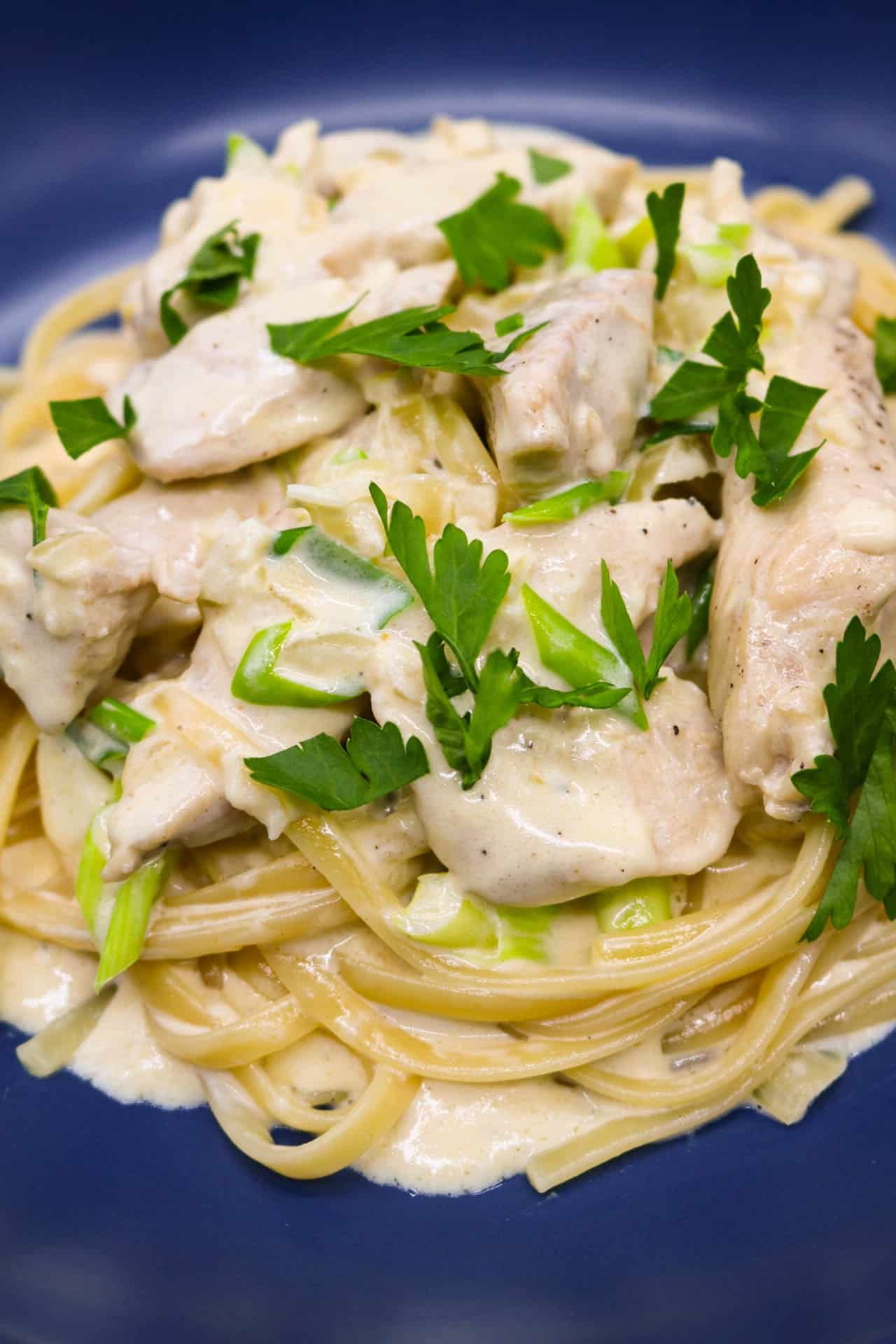 Creamy chicken linguine in blue bowl with yellow napkin at the side
