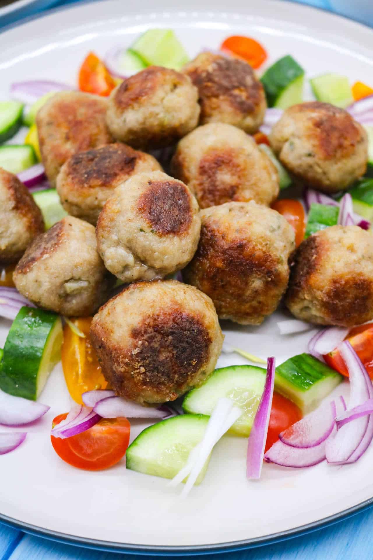 Meze meatbals in plate with onion, cucumber and tomatoes.