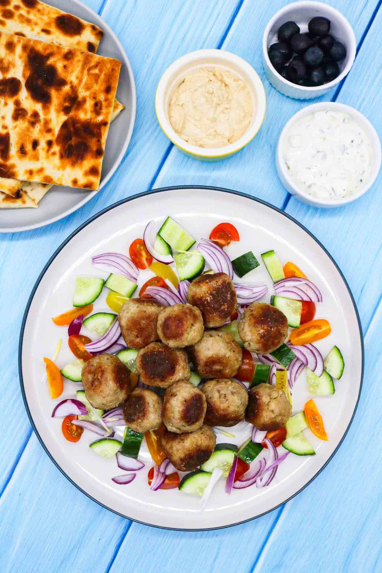 Meze meatbals in plate with onion, cucumber and tomatoes.