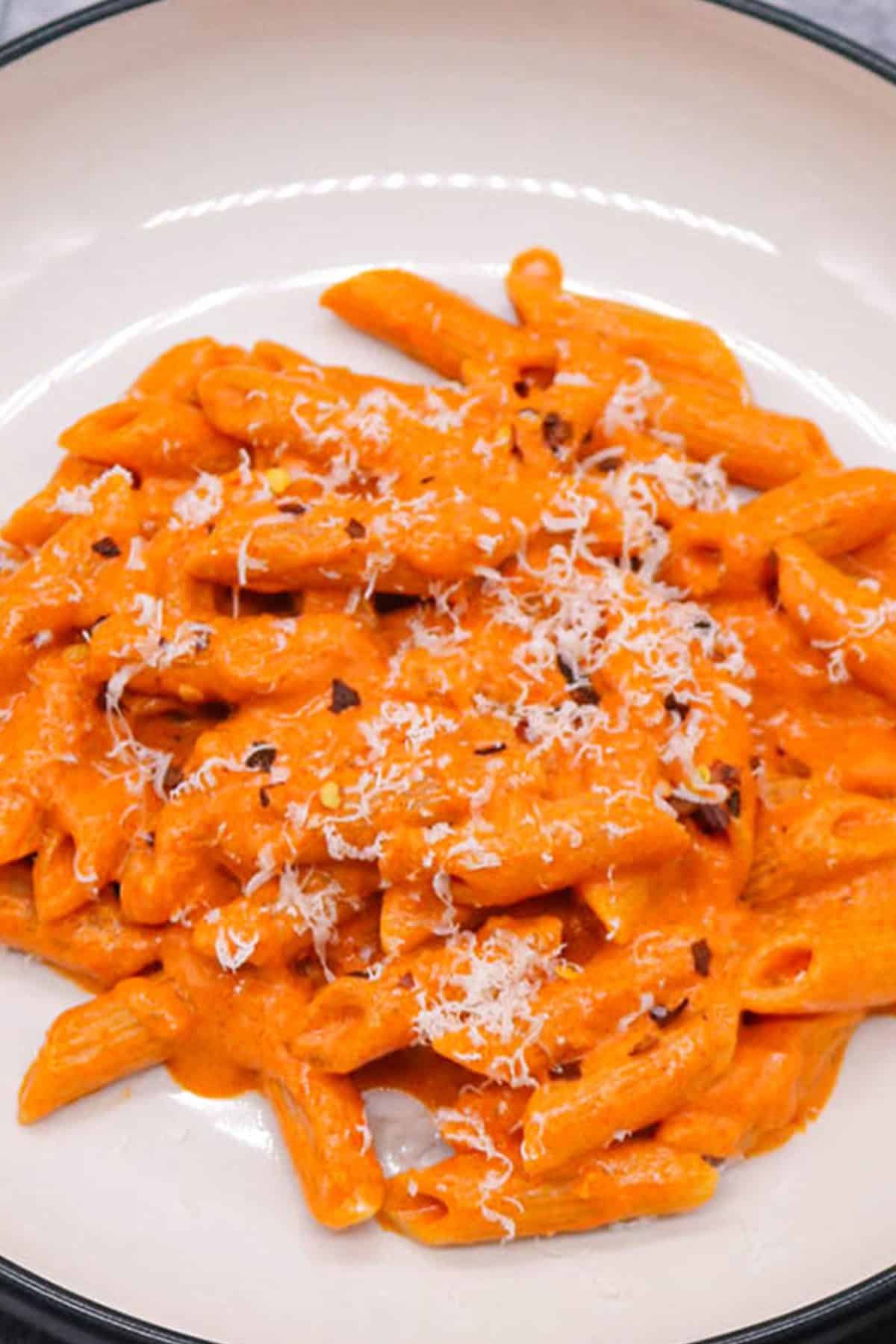 Close photo of penne alla vodka in a black and cream pasta bowl.