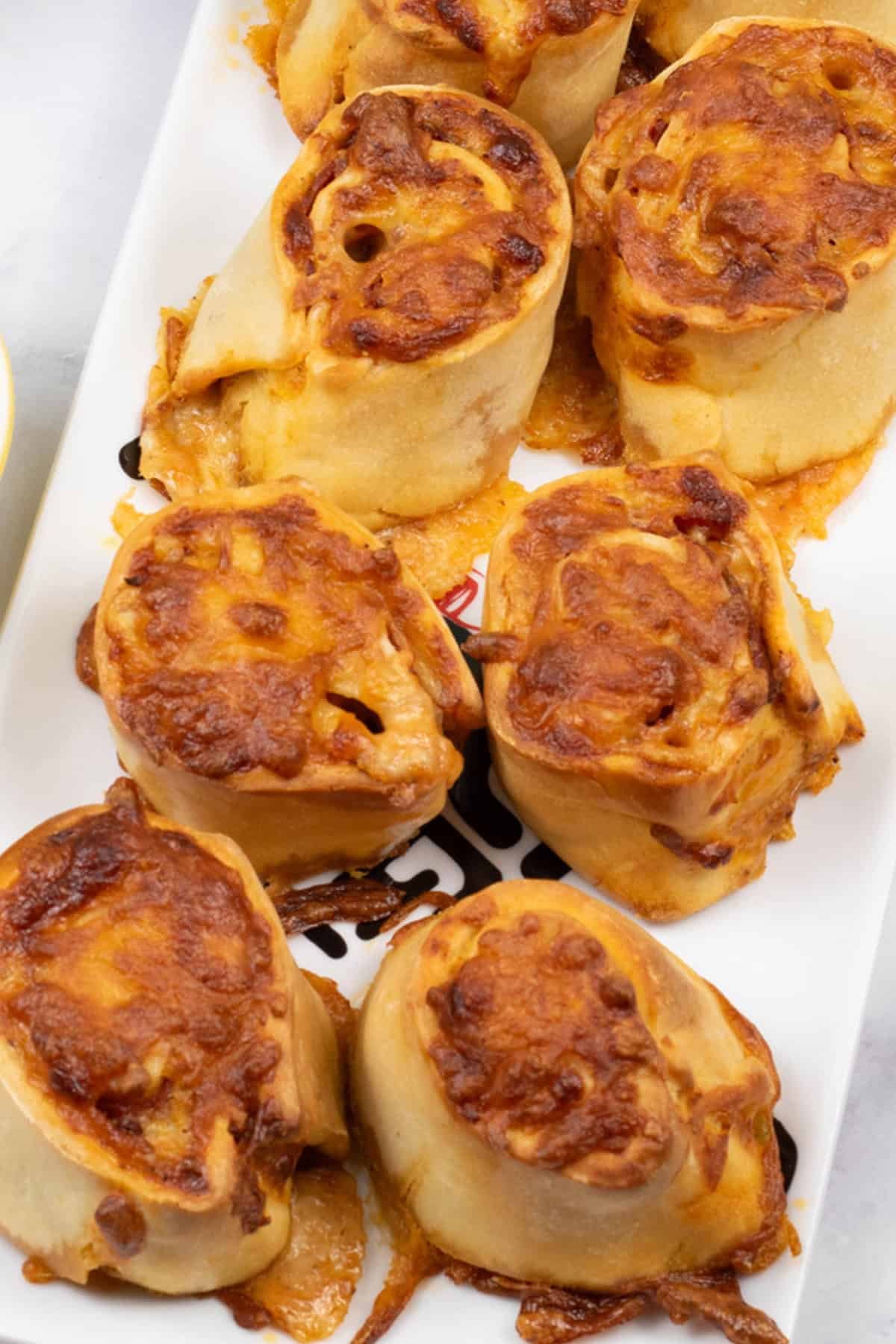 Close up of pepperoni pizza rolls on a rectangle platter.