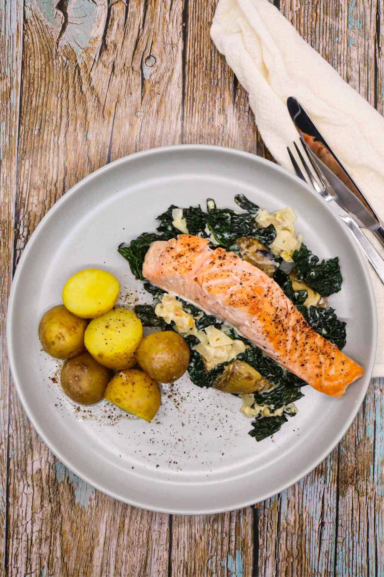Salmon and creamy artichoke sauce with potatoes on grey plate