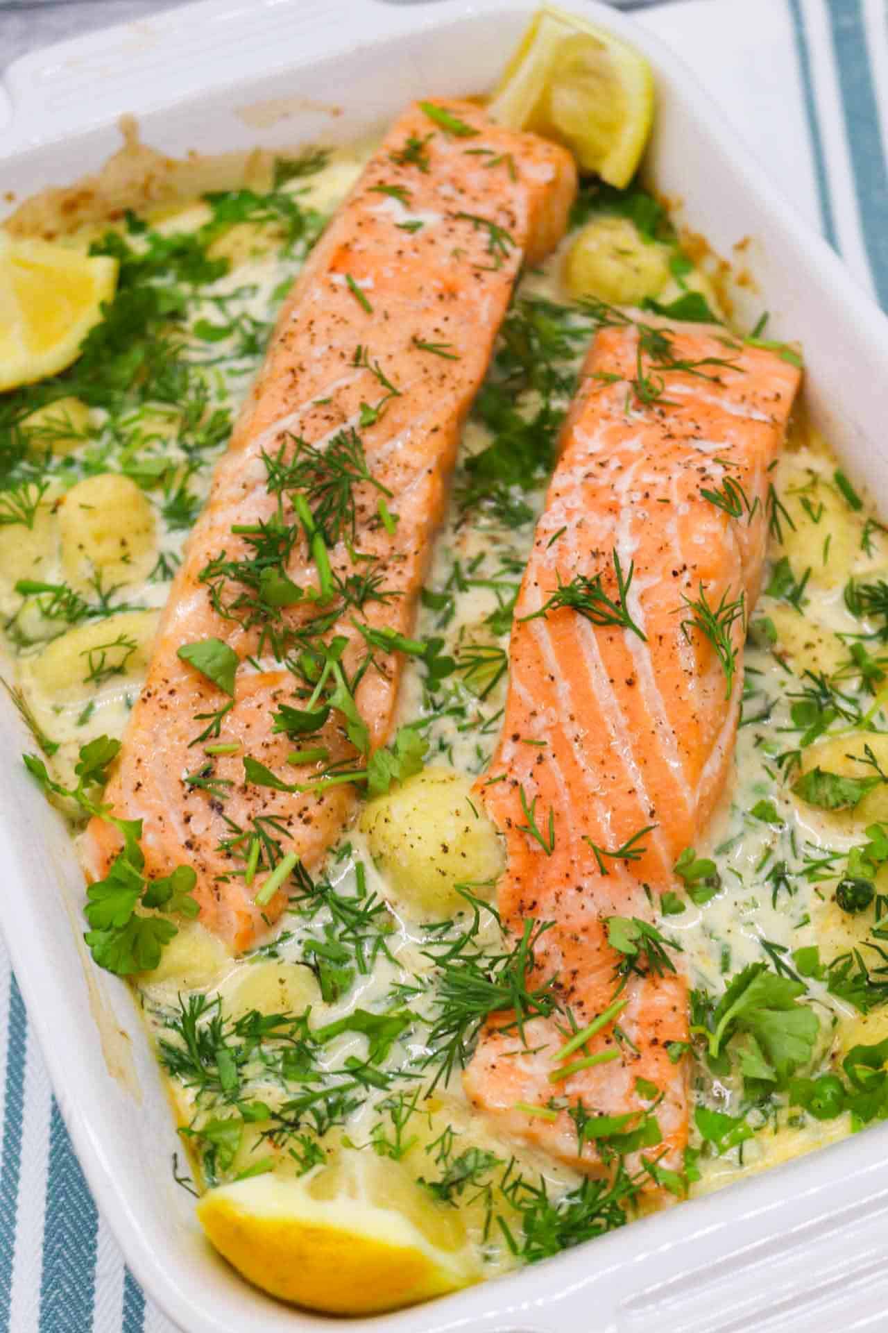 Salmon and gnocchi in rectangle serving dish with lemon wedges