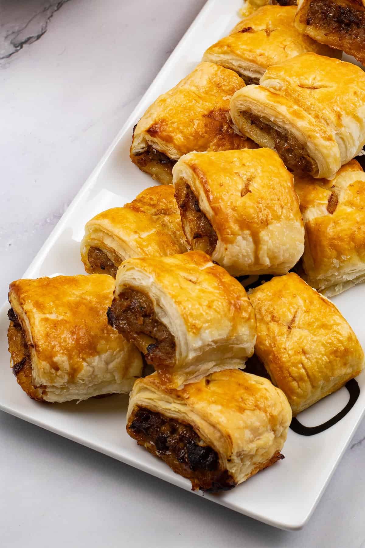 Close up of sausage rolls on a rectangular platter.