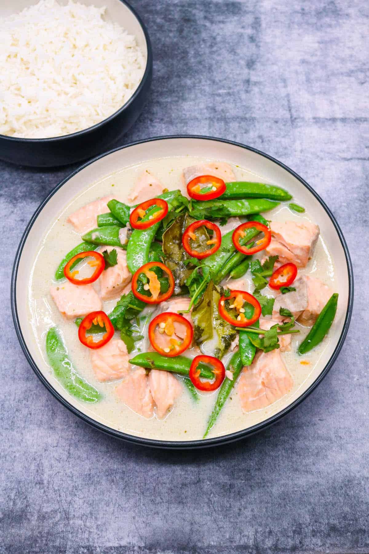 Thai green salmon curry in bowl with green vegetables and sliced red chilli