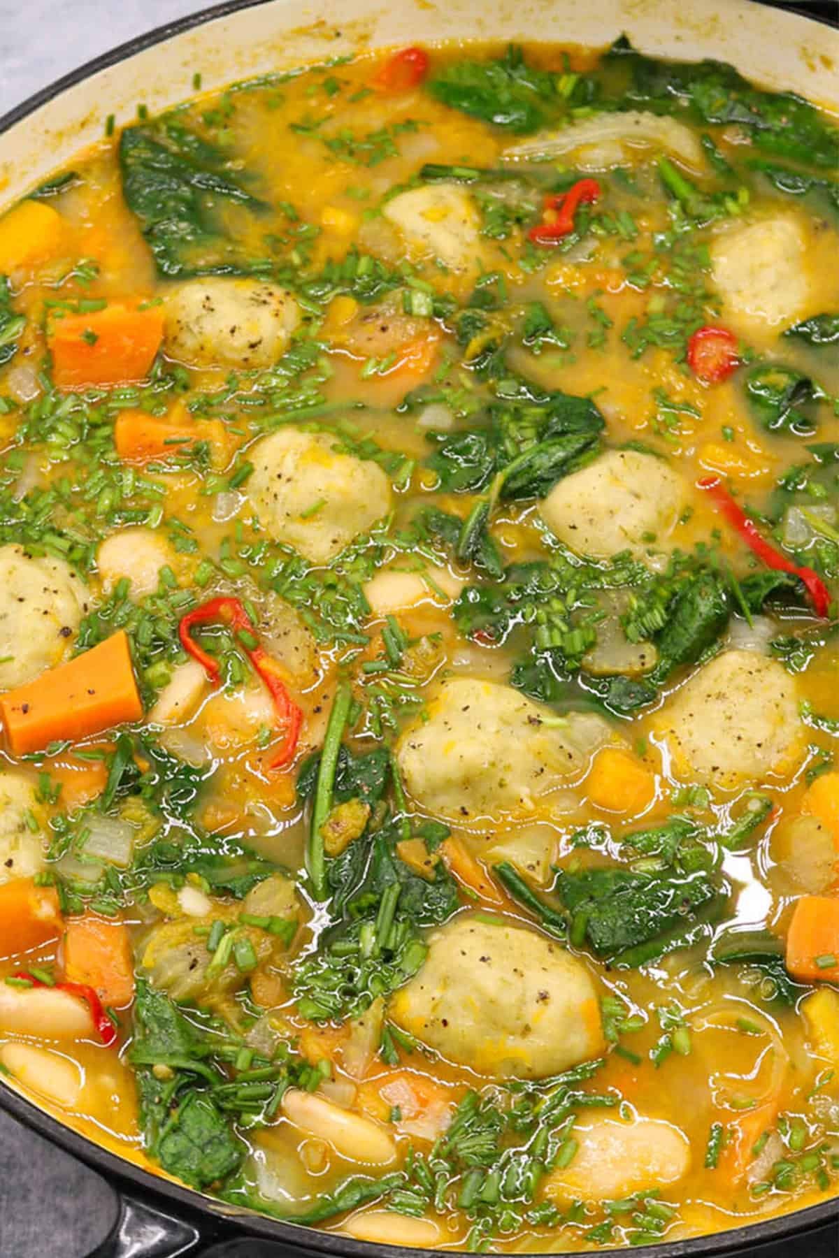Chunky veg stew with cheesy dumplings in a large round casserole.