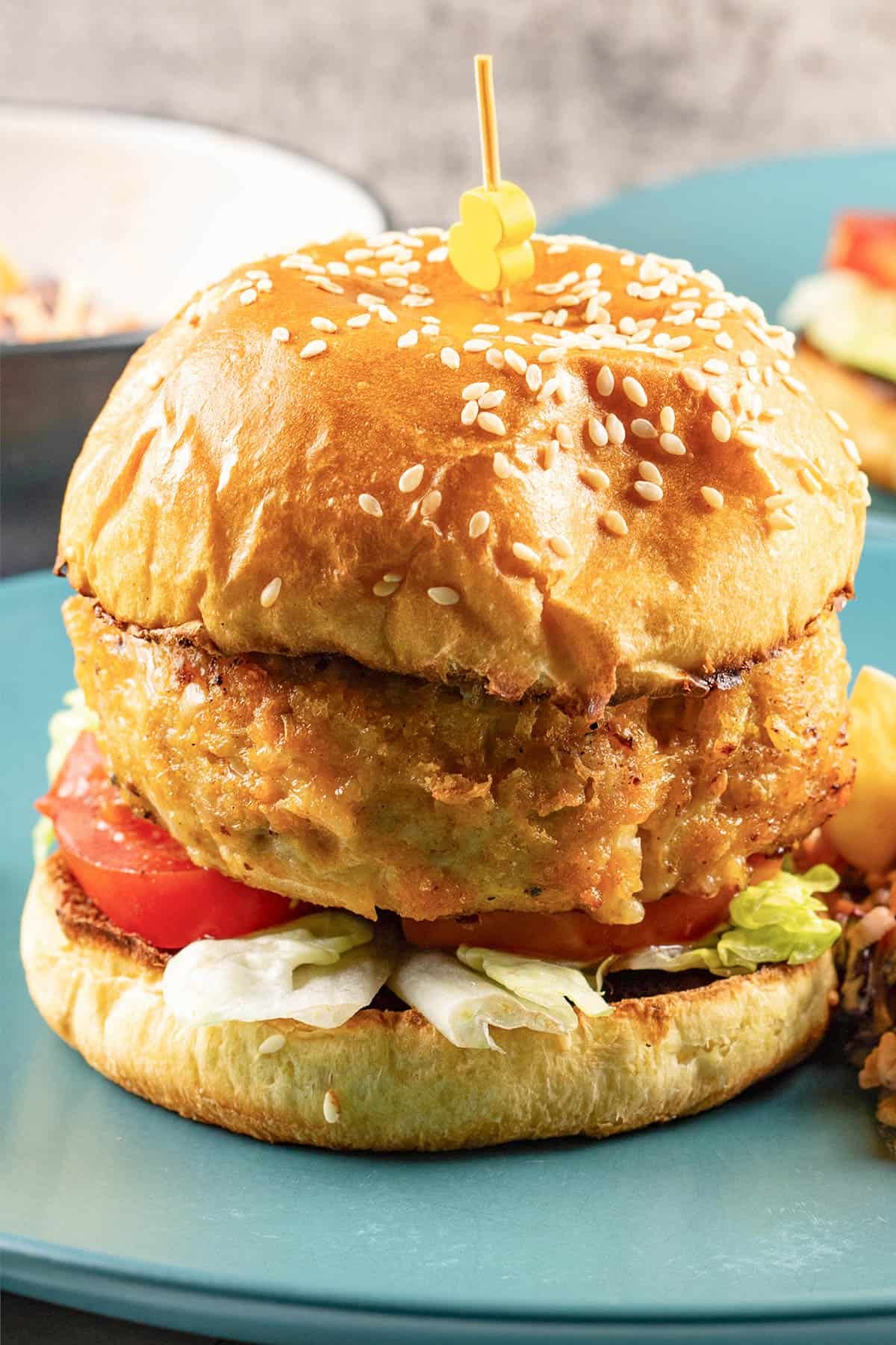 Close up of a buffalo turkey cheeseburger on a teal dinner plate.