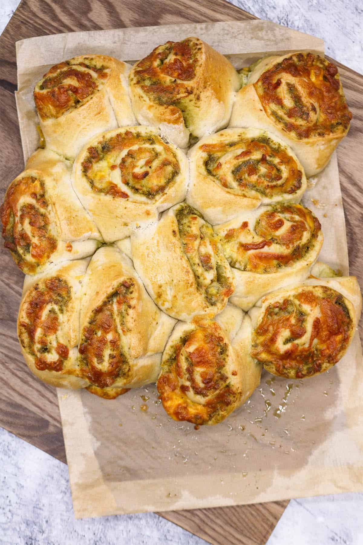 Cheese pesto swirls in baking paper on wooden board