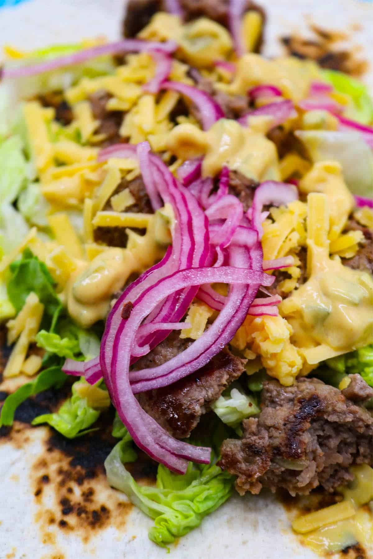 Cheeseburger tacos with red onion, cheese and lettuce