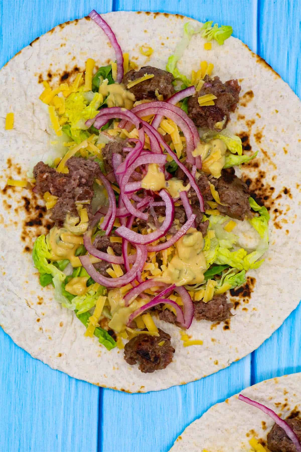 Cheeseburger tacos with red onion, cheese and lettuce