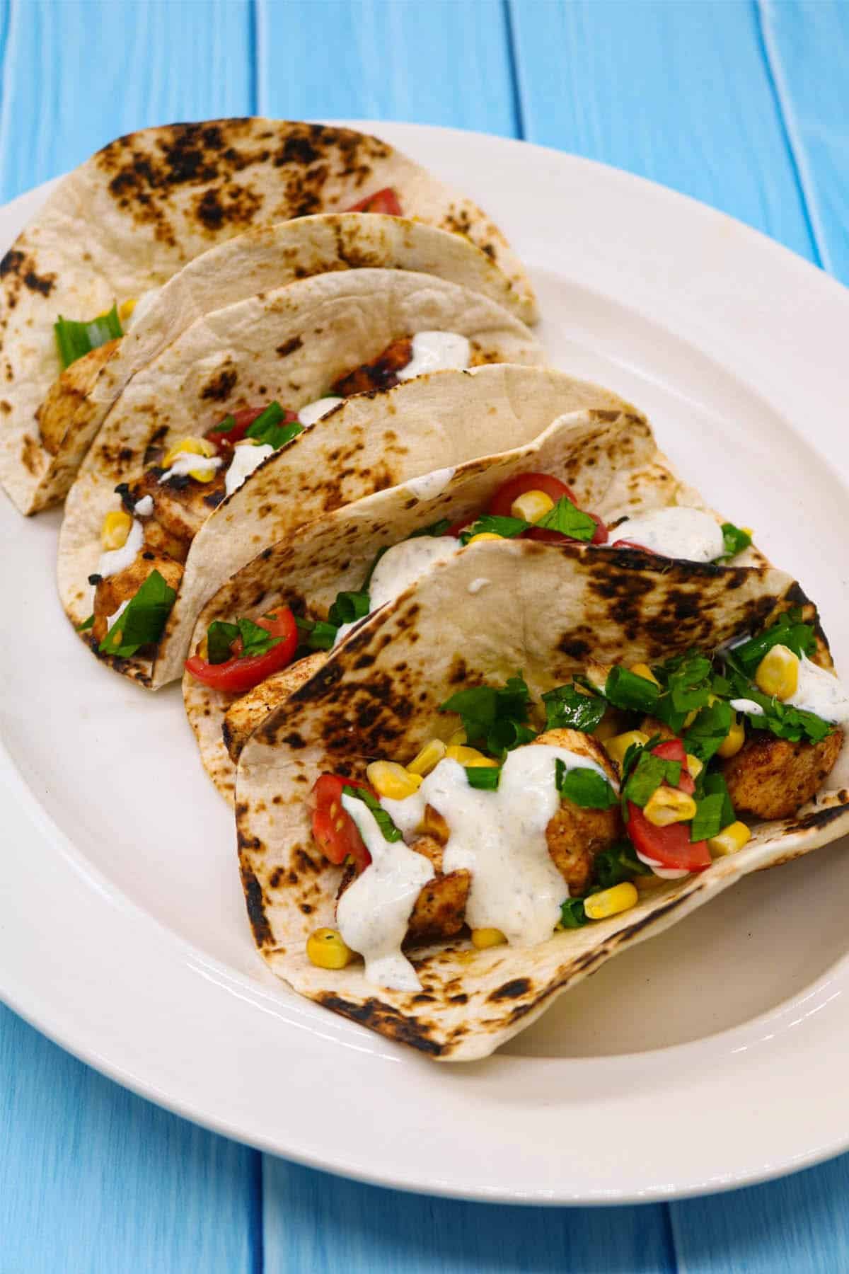 Chicken and corn in flour tortillas on white oval serving platter
