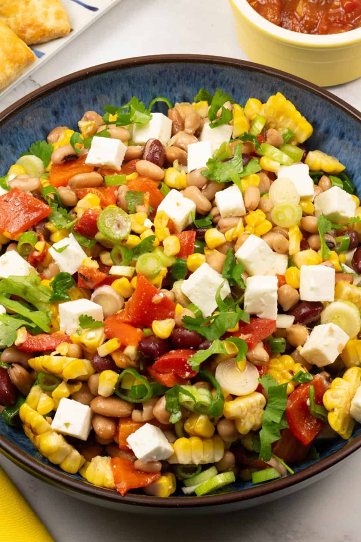 Close up of grilled sweetcorn salad with feta in a blue serving bowl.