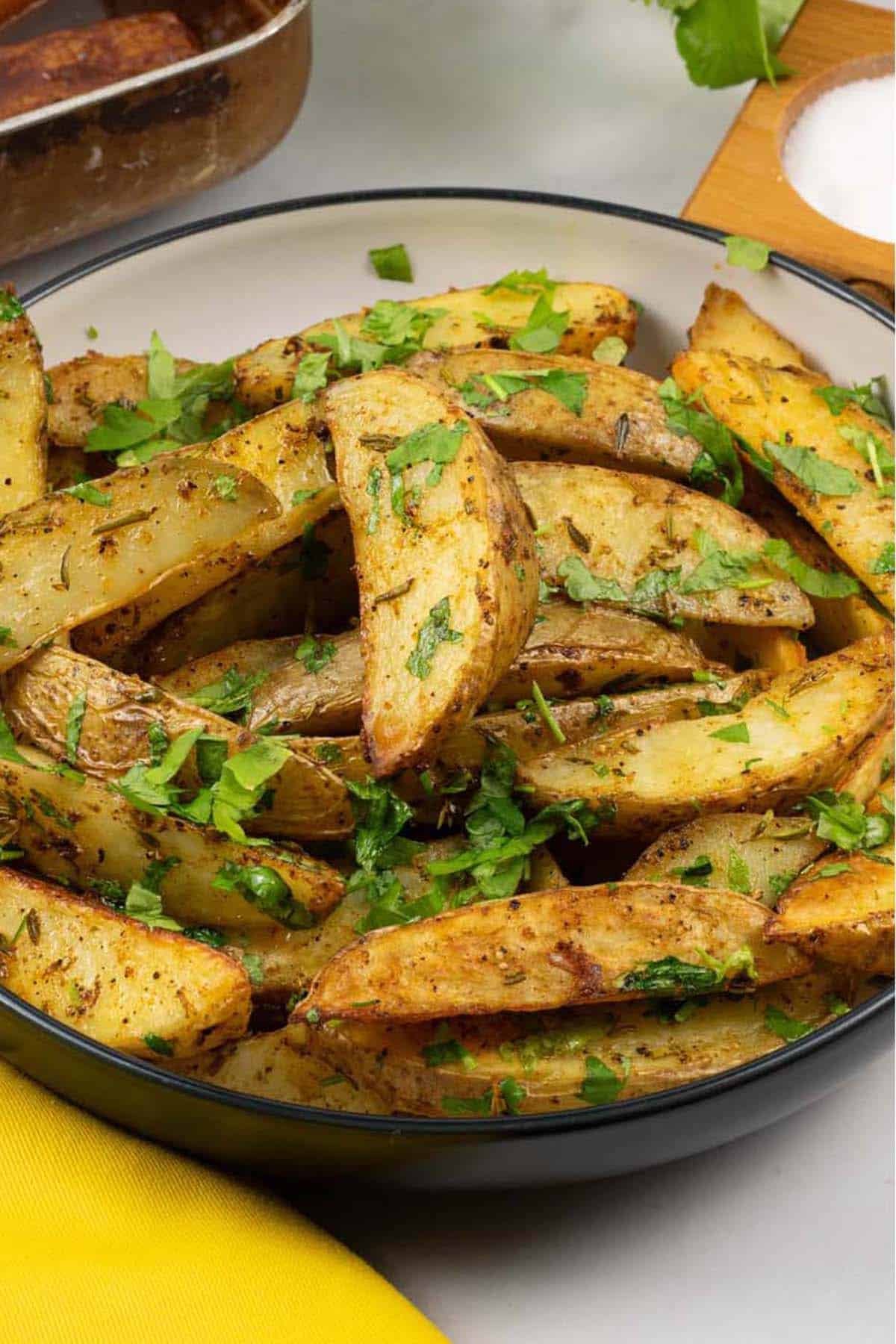 Herby garlic butter potato wedges in a black and cream serving bowl.