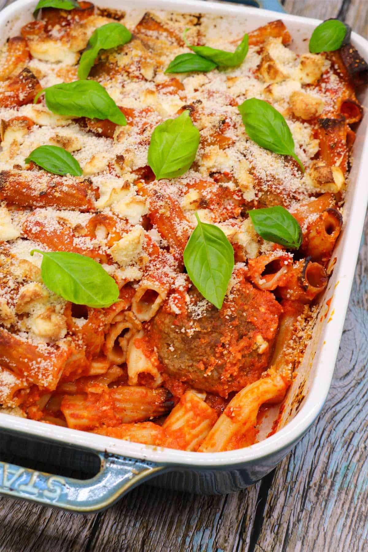 Lamb meatball, red pepper and feta bake in large rectangle oven dish with basil leaves