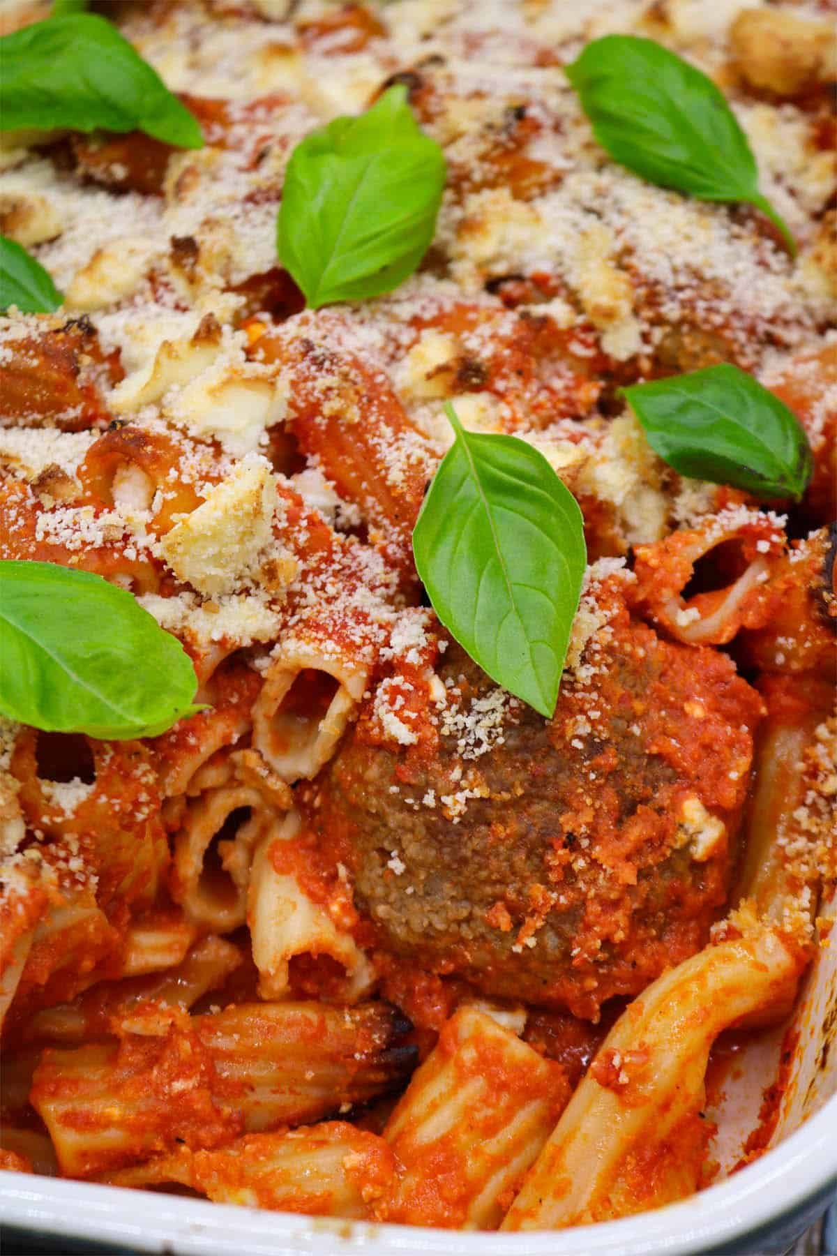 Lamb meatball, red pepper and feta bake in large rectangle oven dish with basil leaves