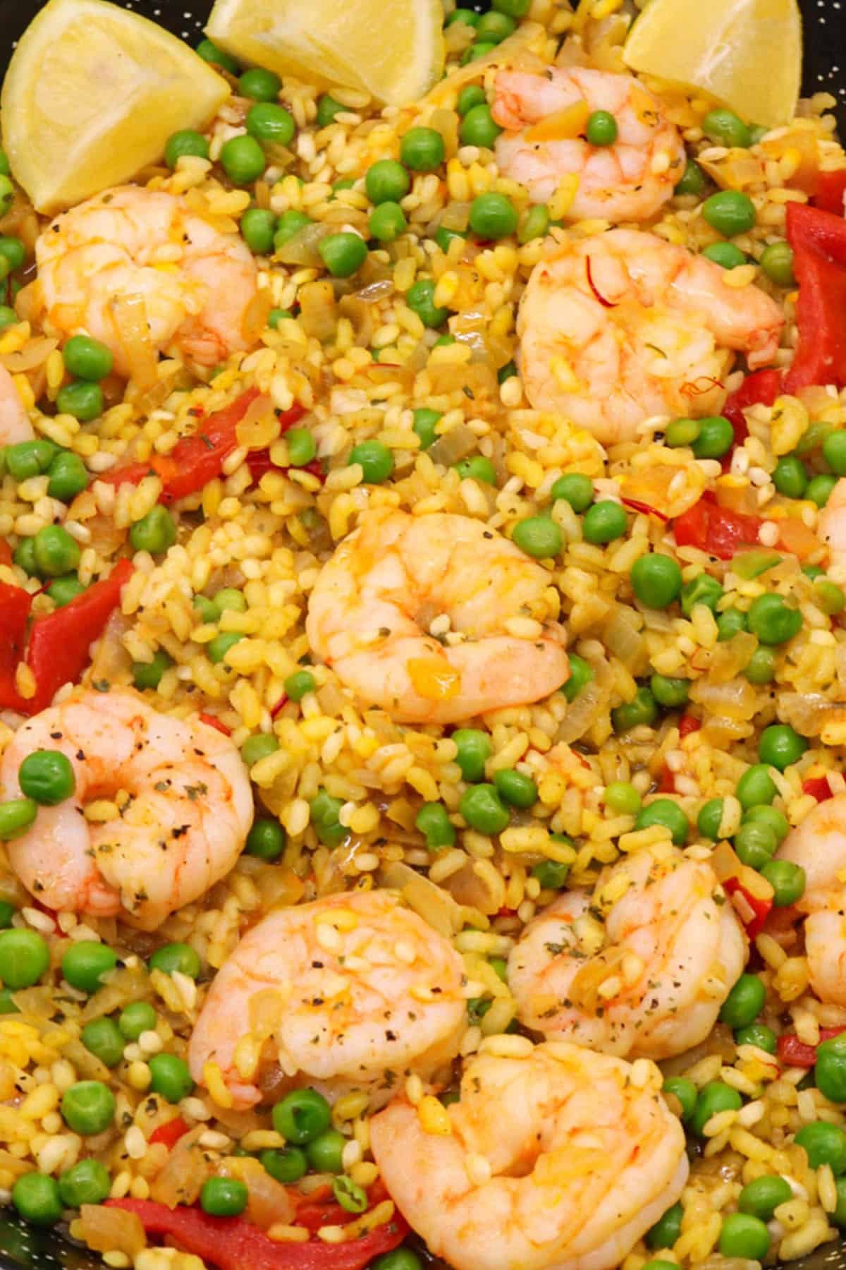 Prawn paella in paella pan with lemon wedges