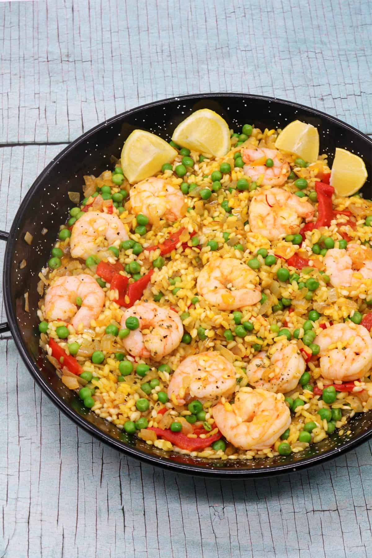 Prawn paella in paella pan with lemon wedges