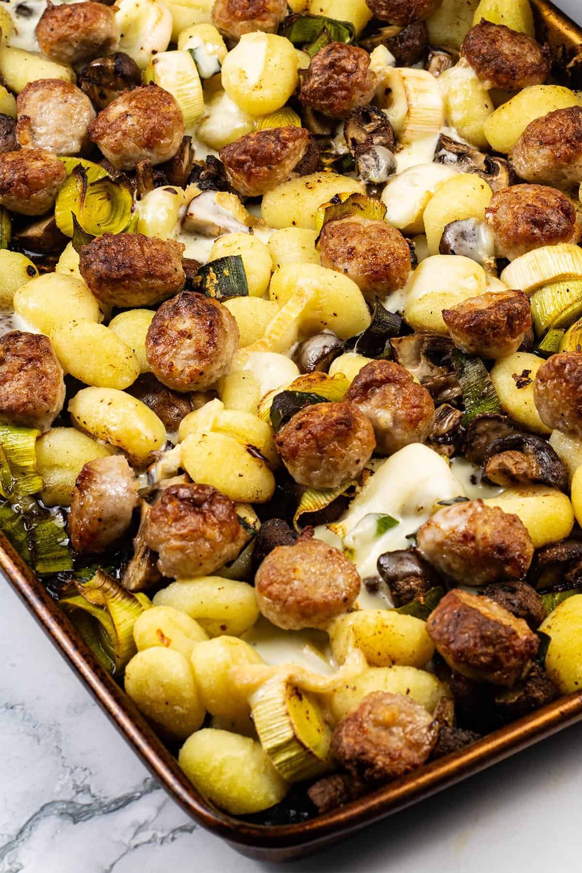 Close up of sausage and taleggio gnocchi bake on a large baking tray.